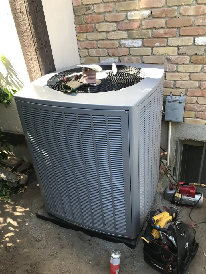 Central air conditioner condenser being serviced with technician tools beside it, a job by I Know A Guy HVAC in the Salt Lake Valley