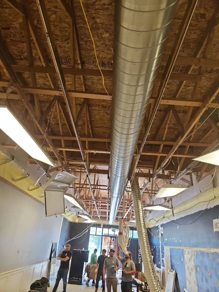 Crew installing a long run of spiral ductwork in a commercial space