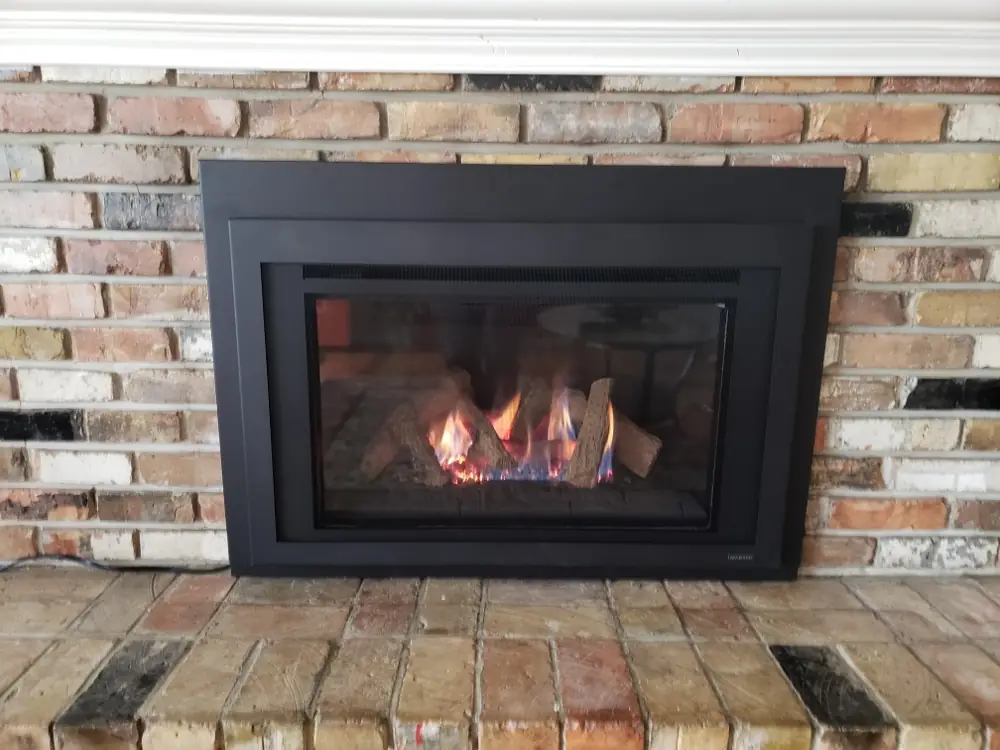 New gas fireplace insert burning in a brick fireplace