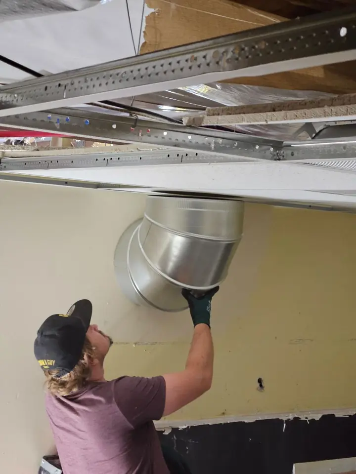I Know A Guy HVAC technician fitting a round duct into a new supply boot